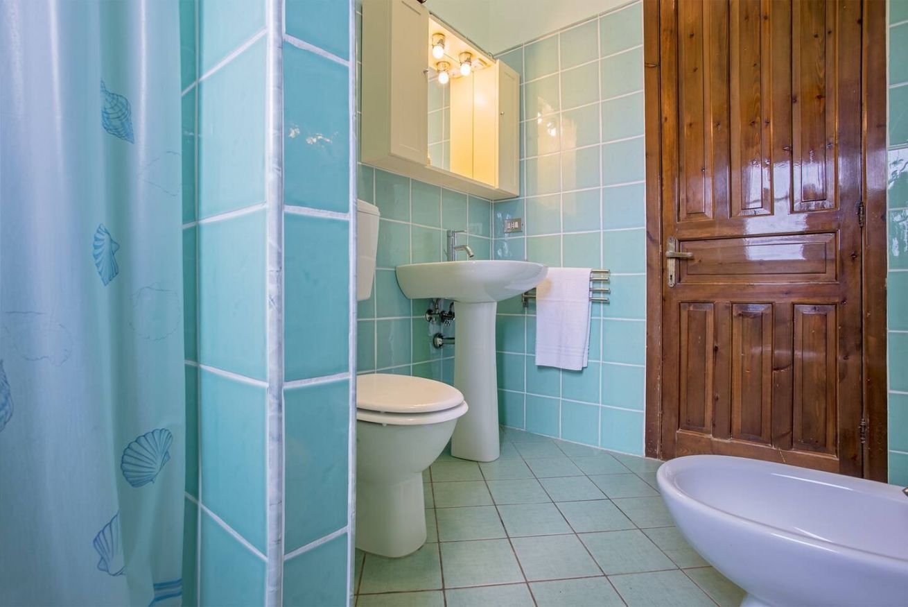 A bathroom with a toilet, sink, and wooden door.