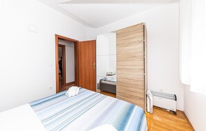 Ein Schlafzimmer mit einem Bett, einem Holzschrank, einem weißen Heizkörper und einer Tür zu einem anderen Raum.