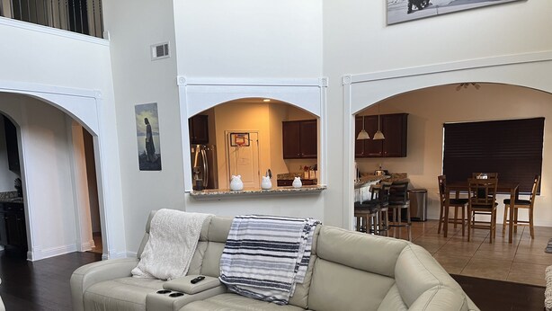 Una sala de estar con un sofá seccional color beige, una mesita y una cocina visible a través de un arco.