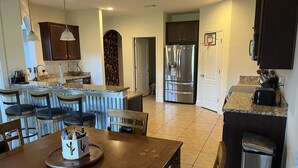 Una cocina moderna con una isla central, taburetes de bar y una mesa de comedor.