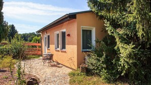 A single-story building with a brick pathway leading to a patio area with outdoor seating. - Ferienwohnung Rheinsberg (Rheinsberg OT Kagar)