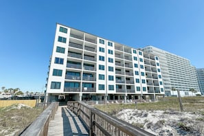 Un hotel de varios pisos con balcones, un muelle de madera y una zona de playa arenosa.