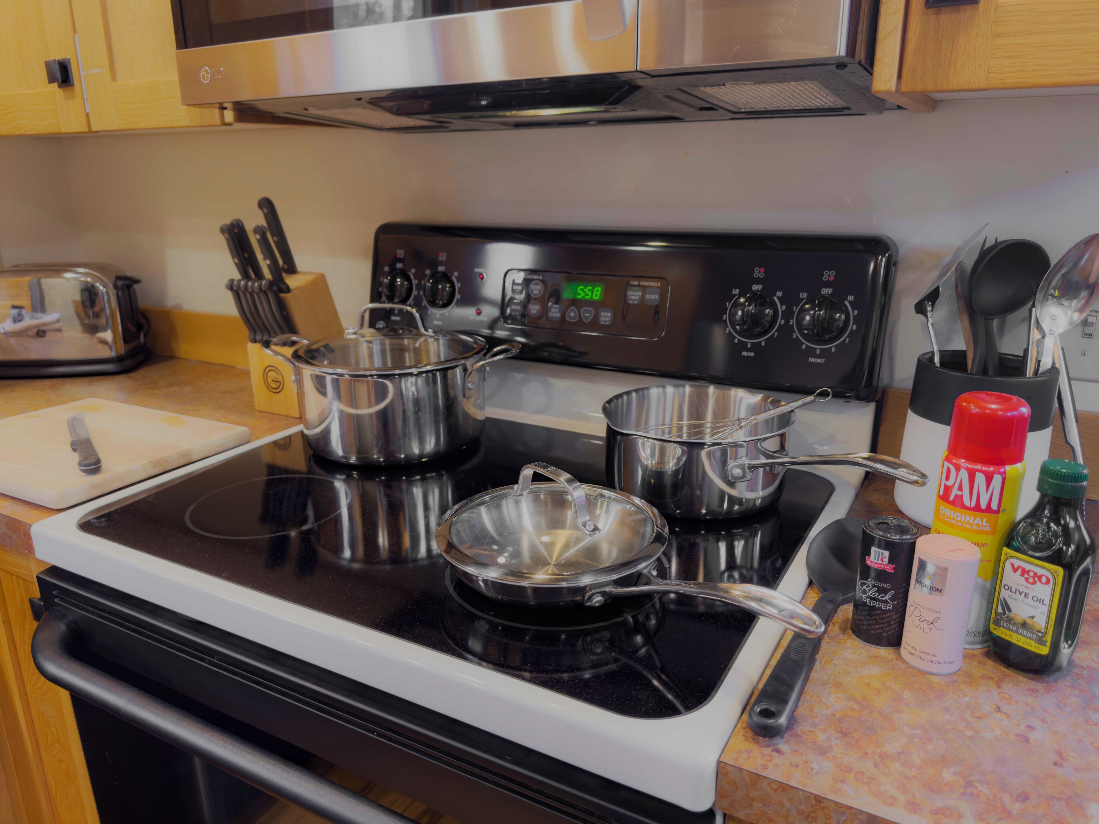 A kitchen with stainless steel appliances, including a stove and pots, and various kitchen utensils.