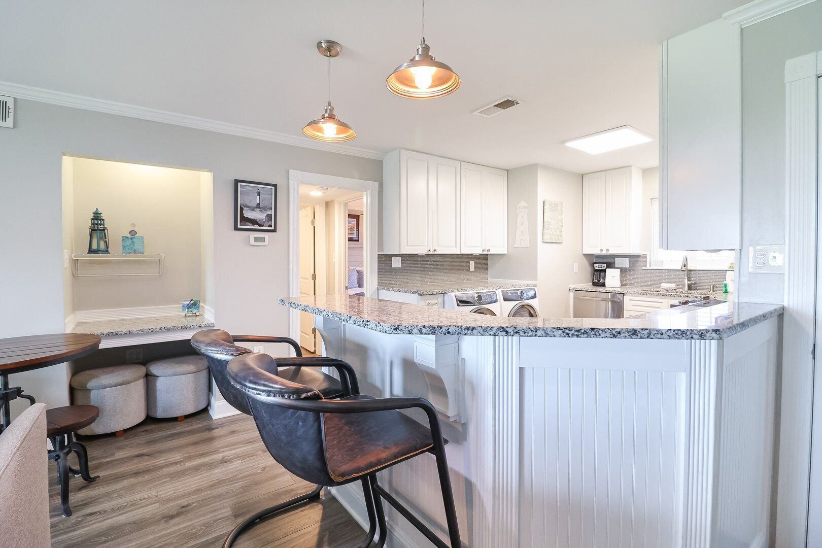 Een moderne keuken met een centraal eiland, barkrukken en hanglampen.