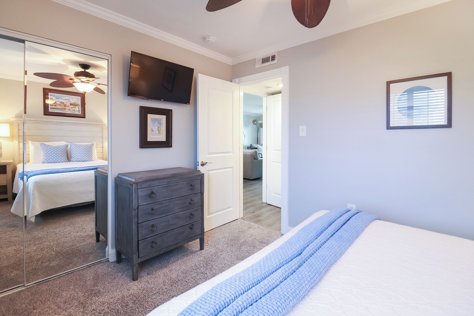 A bedroom with a bed, dresser, and a TV on the wall.