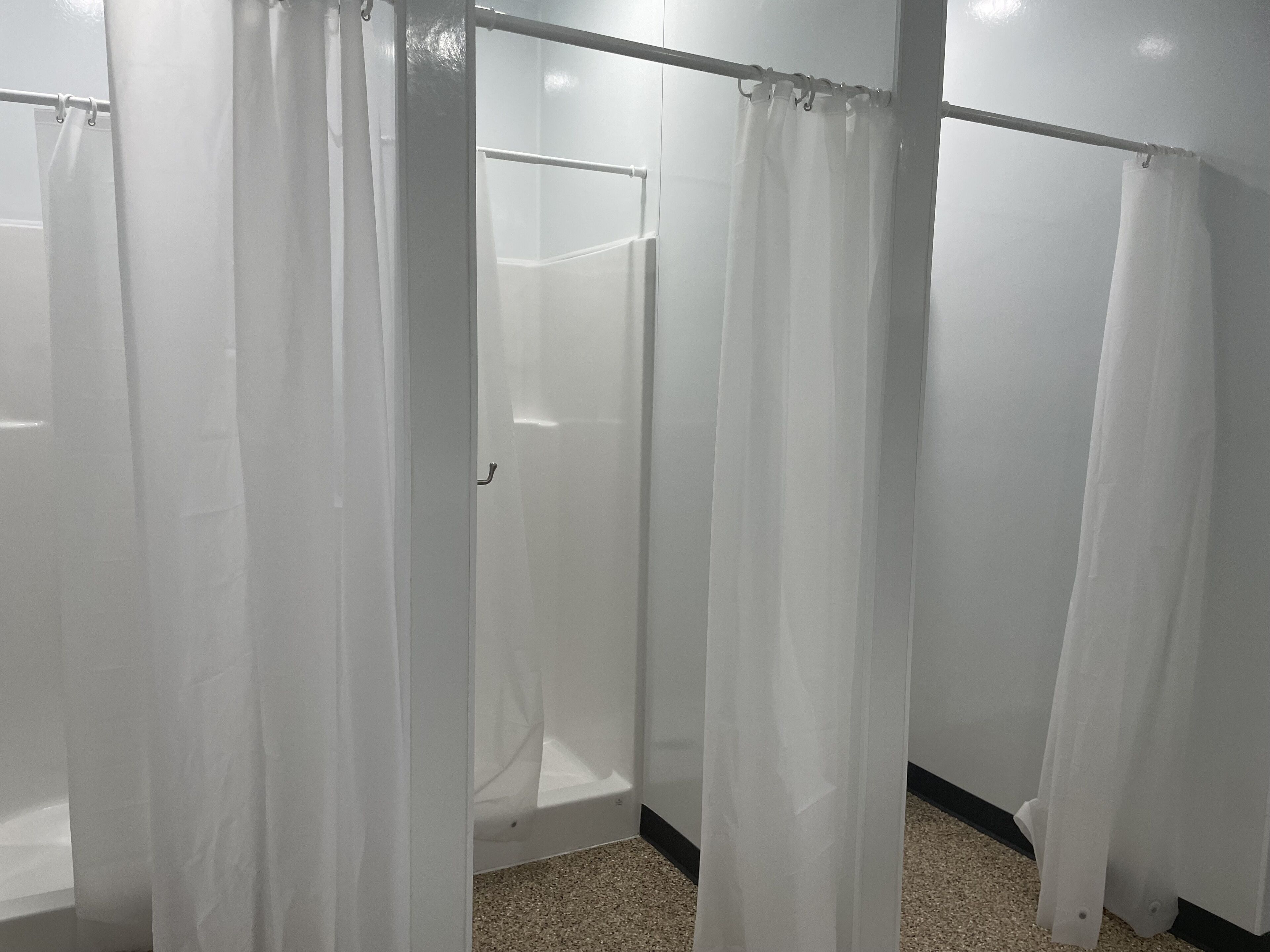Une salle de bain avec des rideaux de douche blancs et une cabine de douche visible.