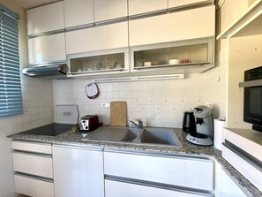 Een koelkast, kookgerei, borden en bestek