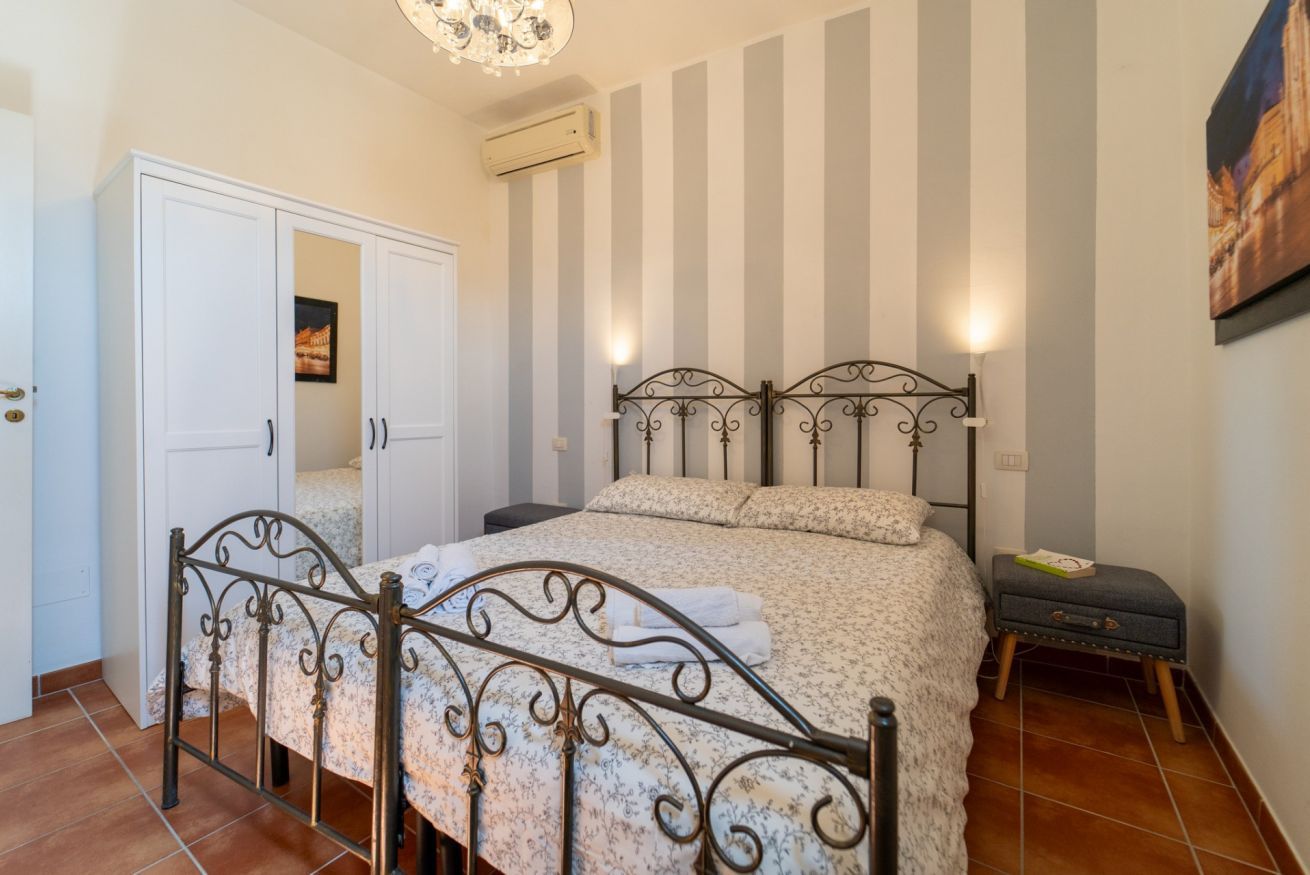 Une chambre à coucher comprenant un lit, une armoire, une table de chevet et un luminaire fixé au mur.
