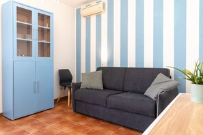 A room with a blue cabinet, a gray sofa, a chair, and a potted plant.