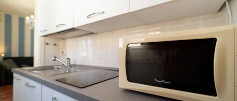 A kitchen with white cabinets, a microwave, and a sink.