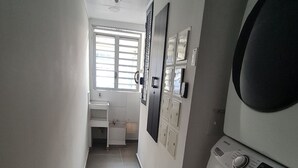 Uma lavanderia com máquina de lavar, secadora e uma pequena mesa com cadeira.