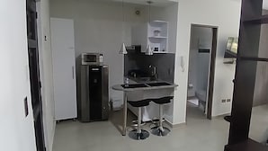 Uma cozinha compacta com micro-ondas, pia e pequena geladeira.