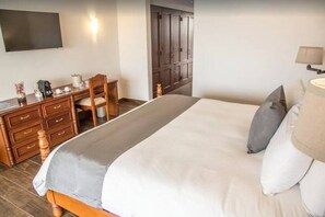 A hotel room with a bed, a desk with a chair, a TV mounted on the wall, and a wardrobe. - 2BDFinisteria Resort Pool & Ocean Views (Cabo San Lucas)