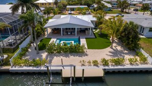 A residential property with a swimming pool, a covered patio, and a dock extending into the water.