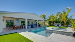 A modern house with a pool, outdoor seating, and palm trees.
