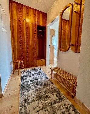 A hallway with a wooden wardrobe, a bench, and a mirror.
