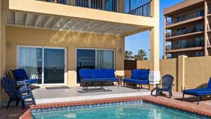 A pool area with blue lounge chairs and a tiled pool edge.