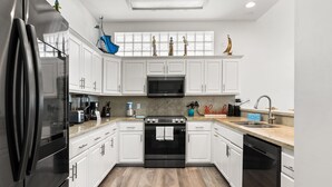 A modern kitchen with white cabinets, a black oven, and a stainless steel refrigerator.