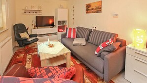 Un salon avec un canapé, un fauteuil, une table basse et un téléviseur.