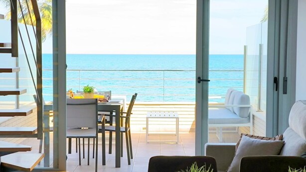 Un interior moderno con balcón que da al mar, con zona de comedor y asientos.