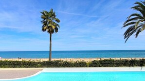Cielo azul despejado, piscina y playa con valla.