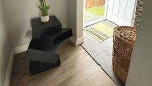 A modern entryway with a dark staircase, a small cactus plant, and a wicker basket.