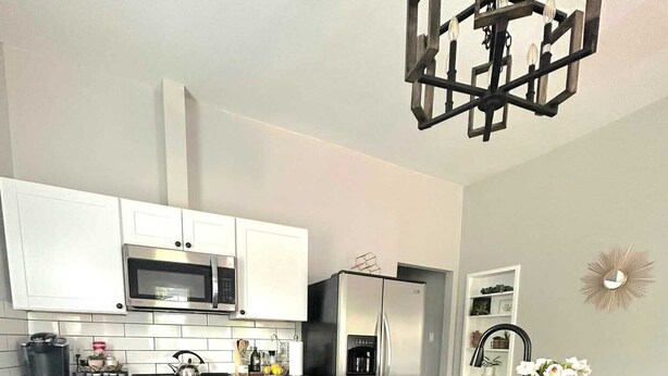 A modern kitchen with white cabinets, stainless steel appliances, and a central island with two brown chairs.