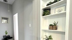 A modern hallway with a built-in white shelving unit displaying plants and decorative items.
