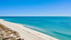A beach with clear turquoise water and a sandy shore. - The Oasis 1506 | Spacious, Lazy River, Poolside Grill, New Splash Pad, Pool with Slide! (Orange Beach)