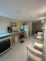 Cocina moderna con estufa a gas, refrigerador y pileta. Hay utensilios colgantes y una cafetera.