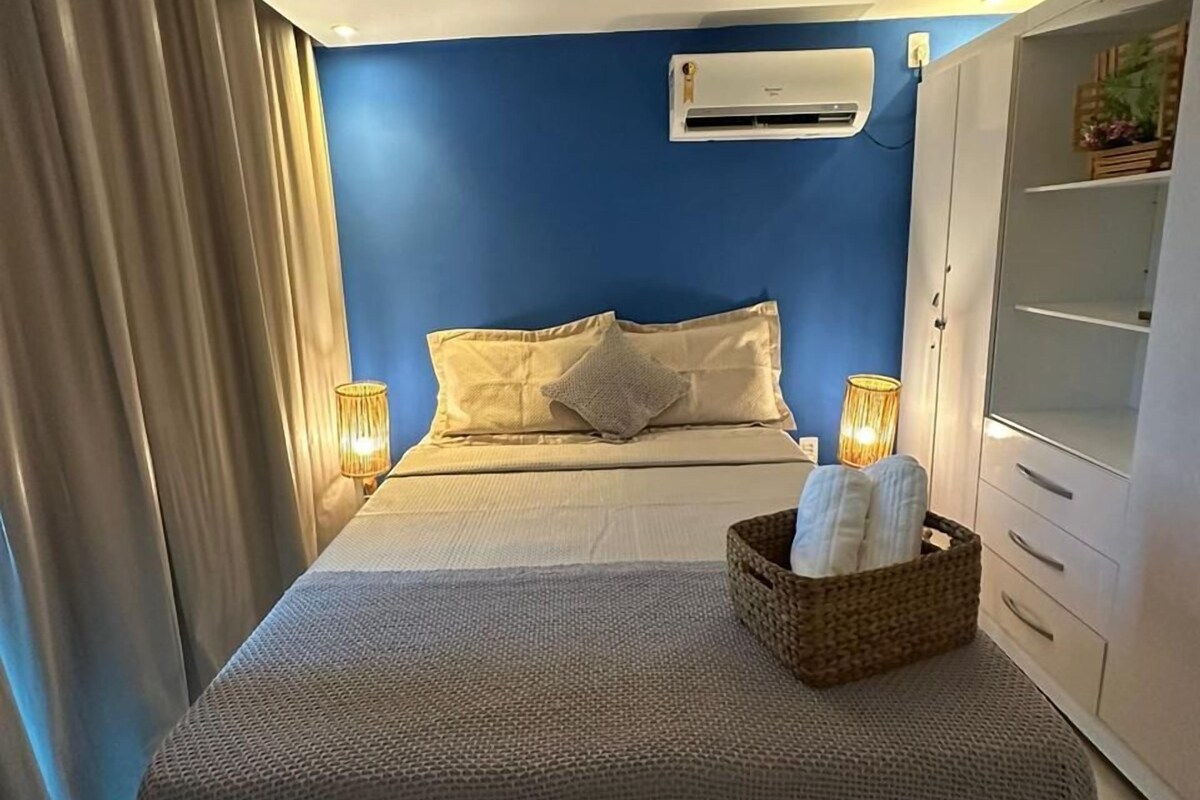 Um quarto com uma cama, abajur, ar condicionado e guarda-roupa.