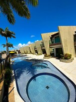 Una piscina de diseño curvo, rodeada de edificios modernos con balcones y zonas de estar al aire libre.