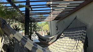 A hammock under a wooden pergola, surrounded by palm trees and a concrete wall. - Beach Flats Porto de Galinhas (Ipojuca)