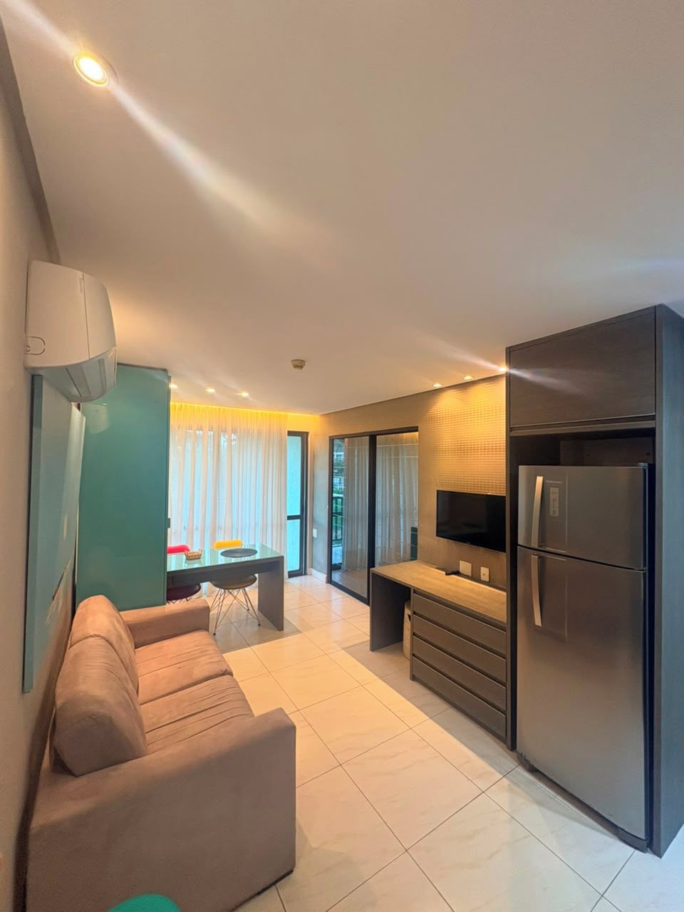 Una cocina moderna con horno empotrado, refrigerador y un comedor con mesa y sillas.