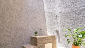 A stone wall with a potted plant and a small step structure. - Seabreeze Boho Stay - Apartment with sea view (Letojanni)