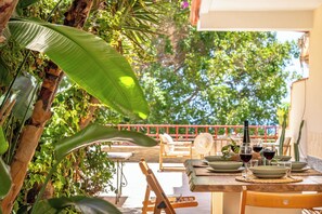 An outdoor dining area with a table set for two, surrounded by lush greenery and a red railing. - Seabreeze Boho Stay - Apartment with sea view (Letojanni)