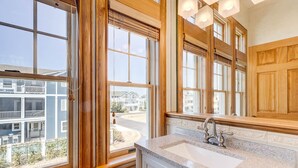 A bathroom with a large window, a sink, and wooden cabinetry. - Beachin Fun (South Unit) | 1665 ft to the beach | Hot Tub, Dog Friendly, and Community Pool (Corolla)