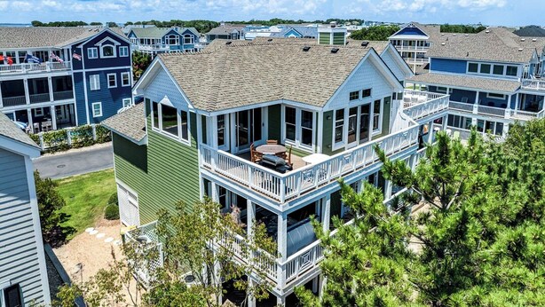 A coastal residential area with multiple two-story houses featuring balconies and large windows. - Beachin Fun (South Unit) | 1665 ft to the beach | Hot Tub, Dog Friendly, and Community Pool (Corolla)