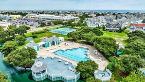 A large resort with multiple swimming pools, a gazebo, and a view of the surrounding town. - Beachin Fun (South Unit) | 1665 ft to the beach | Hot Tub, Dog Friendly, and Community Pool (Corolla)