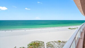 A beach view from a balcony with a clear sky and ocean.
