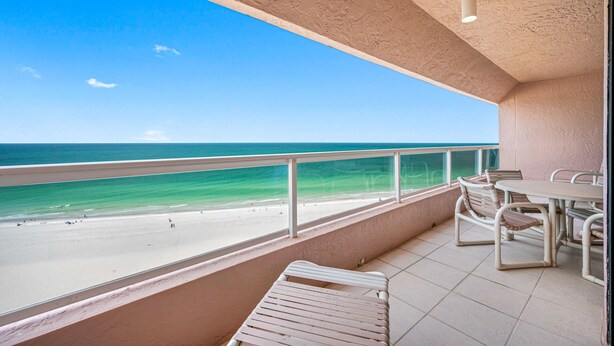 A balcony with a view of the beach and ocean.