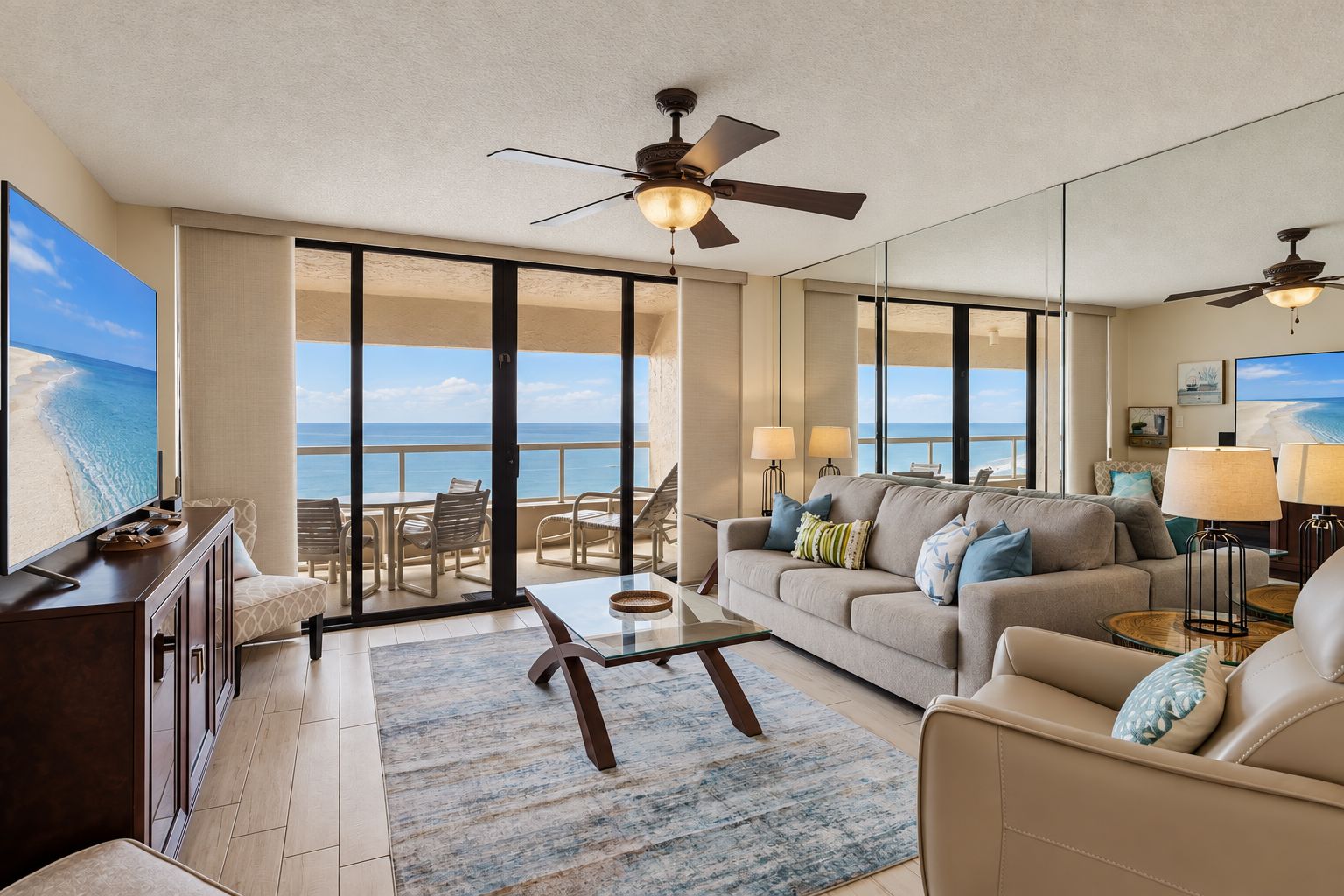 A spacious living area with a balcony overlooking the ocean, furnished with a sofa, coffee table, and lamps.