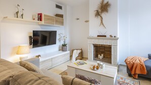A modern living room with a flat-screen TV, a fireplace, and a cozy seating area.