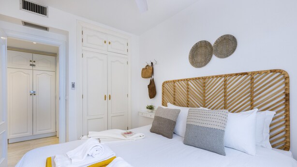 A hotel room with a bed, white wardrobe, and a wooden headboard.