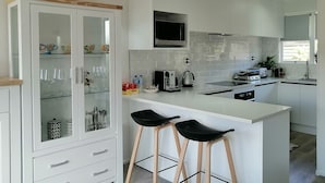 Una cocina moderna con armarios blancos, una isla central con taburetes de bar y un microondas encima de la isla.
