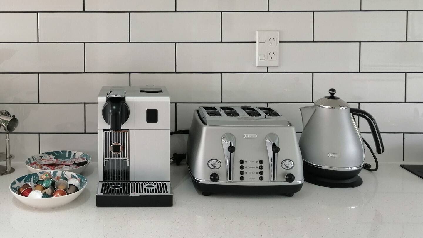 Et køkken med kaffemaskine, brødrister og elkedel på disken.