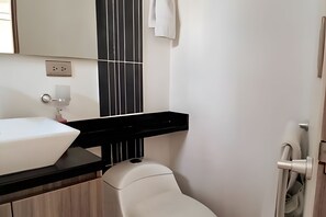 A bathroom with a white sink, black countertop, and a vertical black and white striped panel.