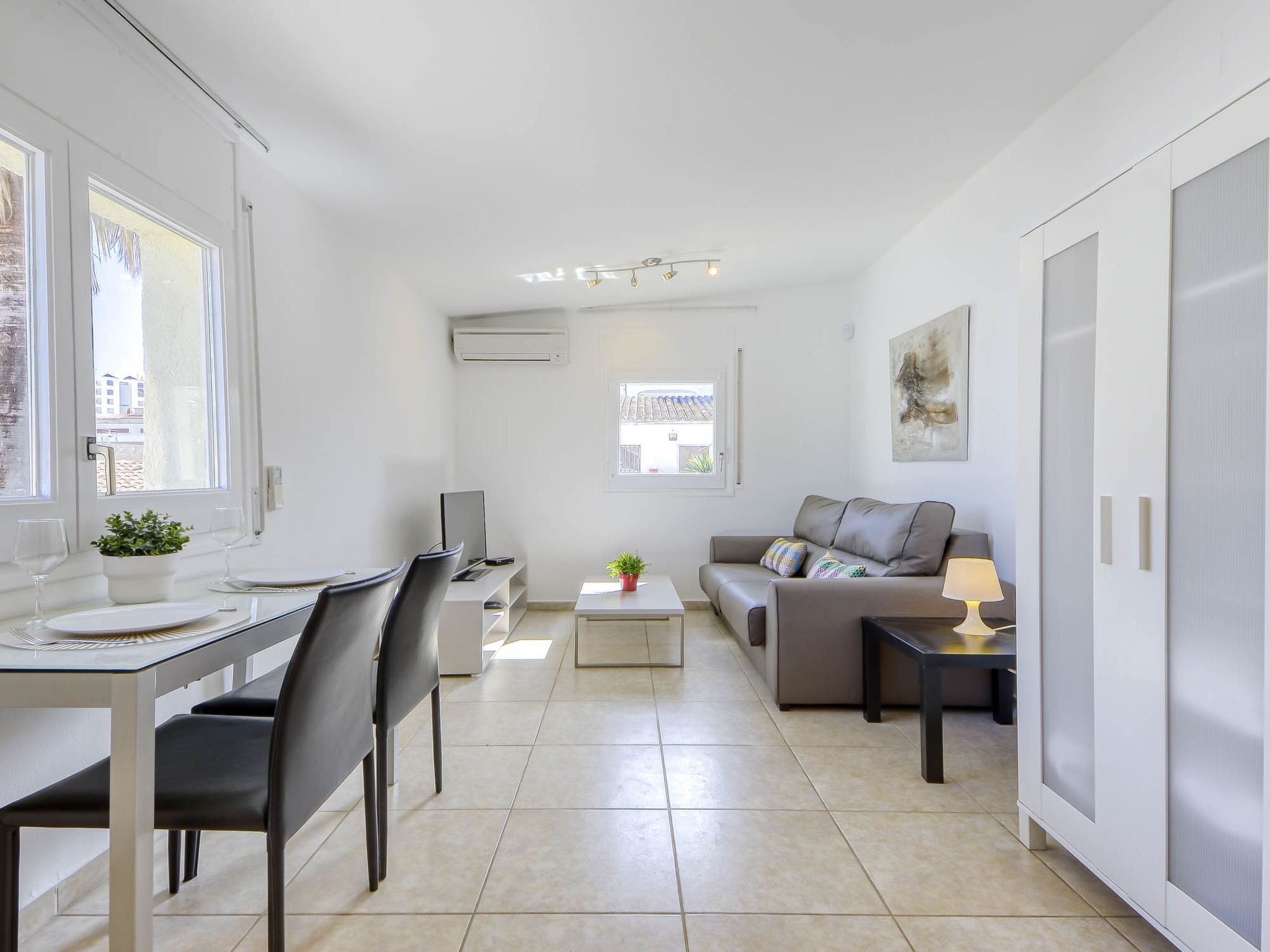 Un salon moderne et bien éclairé, comprenant une table à manger, des chaises, un canapé et une table basse.