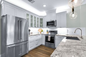 A modern kitchen with stainless steel appliances, white cabinetry, and a granite countertop.