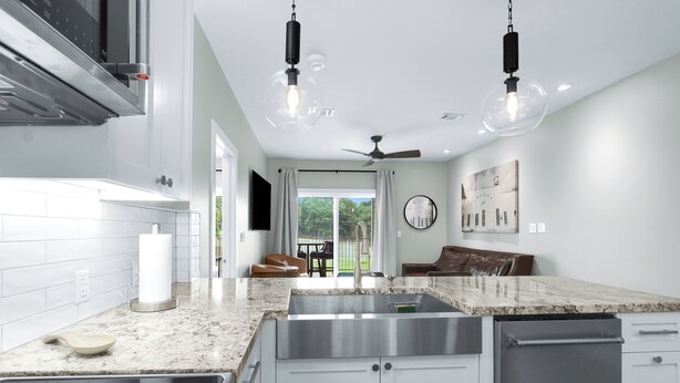 A modern kitchen with a large island, stainless steel appliances, and pendant lighting.